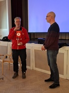 Ammattiosaston puheenjohtaja Rami Häkkilä ojentaa osaston pitkäaikaiselle aktiiville ja entiselle puheenjohtajalle Olavi Parkkilalle ammattiosaston viirin numero 11.